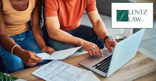 a woman holding a document and a man typing on a laptop