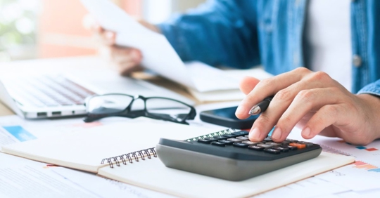 Man using calculator while reviewing financial documents